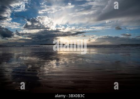 Tramonto sulle vaste spiagge di Essaouira con cieli blu, nuvole bianche e onde che si infrangono sulla riva del Marocco Foto Stock
