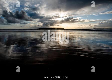 Tramonto sulle vaste spiagge di Essaouira con cieli blu, nuvole bianche e onde che si infrangono sulla riva del Marocco Foto Stock