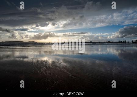 Tramonto sulle vaste spiagge di Essaouira con cieli blu, nuvole bianche e onde che si infrangono sulla riva del Marocco Foto Stock