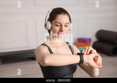 Donna che controlla il fitness tracker durante l'allenamento in casa Foto Stock