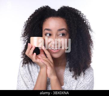 Bella donna brasiliana con barattolo di crema al collagene su sfondo bianco Foto Stock