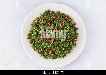 Insalata levantina vegetariana con quinoa, pomodori, melograno, prezzemolo, limone e condimento Foto Stock