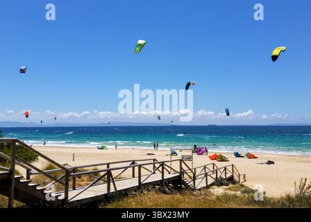 Colorata scena di kitesurf a Tarifa in Spagna con aquiloni in acqua e sulla spiaggia Foto Stock