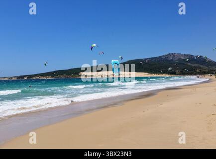 Colorata scena di kitesurf a Tarifa in Spagna con aquiloni in acqua e sulla spiaggia Foto Stock