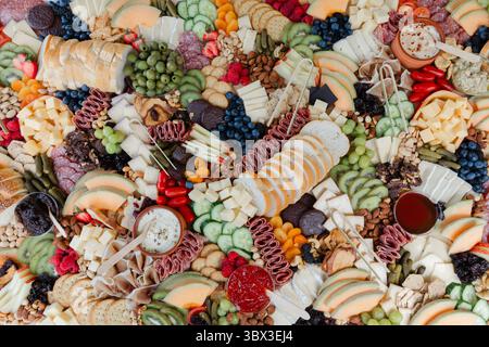 Una vivace esposizione di formaggi assortiti, frutta fresca e spuntini mette in mostra l'arte culinaria durante un incontro sociale. Foto Stock