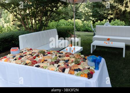 Le riunioni di festa presentano un assortimento splendidamente organizzato di formaggi, frutta e decorazioni in un giardino lussureggiante. Foto Stock