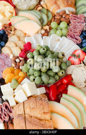 Un variopinto assortimento di frutta, formaggi e affettati è esposto elegantemente su un grande piatto durante una riunione. Foto Stock