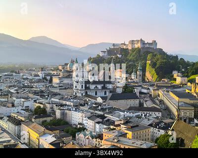 Vista di Salisburgo dalla collina di Monchsberg all'alba, con cattedrale, castello e colline sullo sfondo in una mattinata di sole Foto Stock