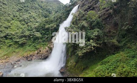 Una cascata tropicale mozzafiato si estende lungo una lussureggiante montagna verde nelle Ande colombiane. Foto Stock