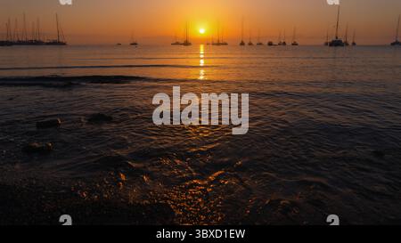 Calmo tramonto sul mare calmo con barche a vela Foto Stock