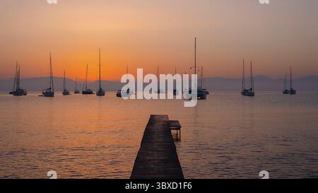 Tramonto sul mare calmo con barche a vela Foto Stock