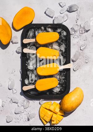 Vista dall'alto del vassoio di papaveri di mango su sfondo bianco al sole. Foto Stock