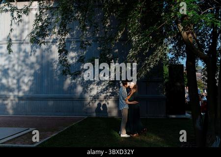 La coppia gode di momenti romantici sotto gli alberi alla luce della sera Foto Stock