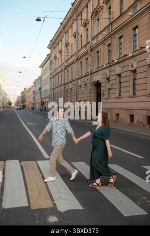 Coppia che attraversa una strada tranquilla insieme durante il tramonto in una città Foto Stock