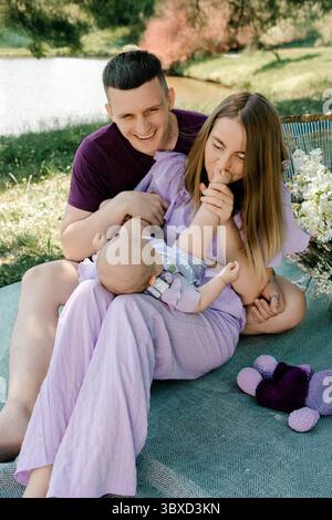 I giovani genitori ridono con il bambino durante il picnic Foto Stock