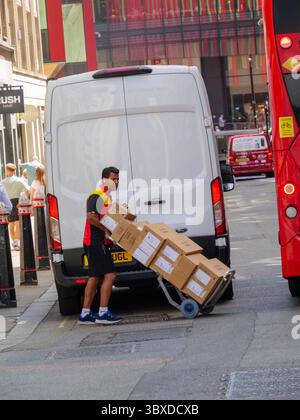 Un corriere DHL scarica i pacchi da un furgone di consegna per distribuirli agli uffici e alle aziende della City di Londra, Regno Unito, supportando la logistica rapida che consente al distretto finanziario di Londra di funzionare senza intoppi Foto Stock