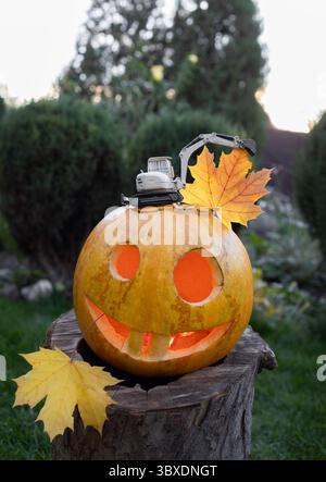 Modello giocattolo in metallo di escavatore su zucca arancione scolpita Halloween con faccia spaventosa e sorridente. Il concetto di festa di Halloween per le imprese edili. Affari Foto Stock