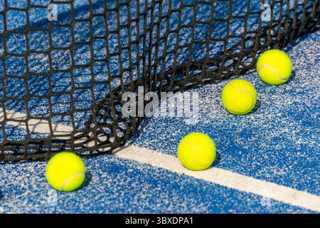 Più palle di Padel gialle su un campo vuoto palle di Padel su un campo blu vicino alla linea bianca Foto Stock