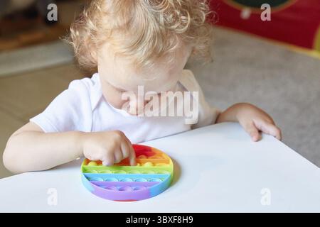 Popolare giocattolo anti stress Pop it. Bambino che gioca con il giocattolo Pop IT Fidget. Felice infanzia, giochi educativi popolari Foto Stock