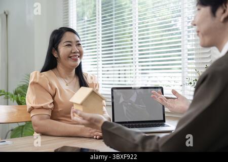 Un agente immobiliare discute con un cliente i vantaggi della proprietà immobiliare, fornendo informazioni utili per decisioni informate sugli investimenti immobiliari Foto Stock