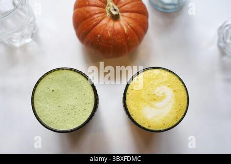 Bevanda sana curcuma e zenzero giallo latte con latte di cocco e vegano matcha latte con tè verde e latte d'avena, vista dall'alto, sfondo bianco, chiudere Foto Stock