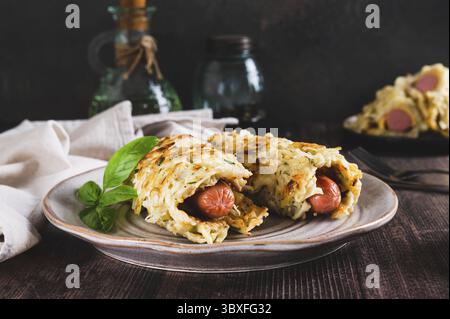 Cibo, salsicce avvolte in frittelle di cavolo grattugiate su un piatto su un tavolo Foto Stock