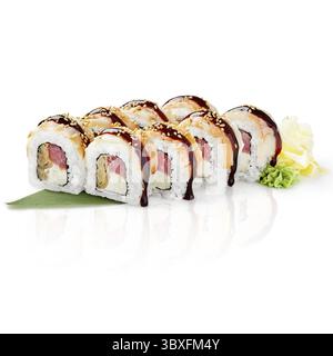 Gli involtini freschi di sushi uramaki con anguilla, semi di sesamo e salsa unagi sono splendidamente presentati su una foglia di bambù Foto Stock