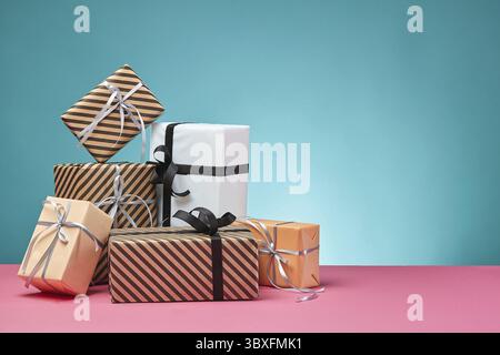 Dimensioni differenti, colorati a strisce e pianura, marrone, rosa e bianco carta scatole regalo legato con nastri multicolori e archi su una superficie di colore rosa e Foto Stock