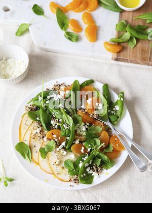 Insalata di spinaci e quinoa con pere, arance e ricotta. Preparazione pasto sano. Piatti a base di piante. Vita verde. Ricetta vegana. Styling alimentare. Vegetariano Foto Stock