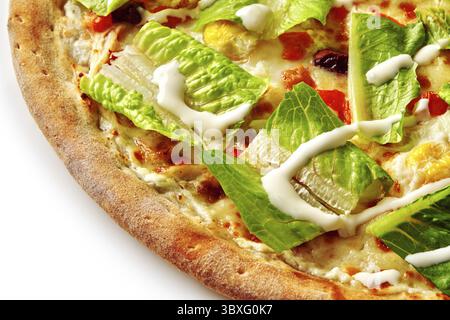 Primo piano di un'appetitosa pizza caesar con lattuga romaina fresca, condimento cremoso e crosta dorata Foto Stock