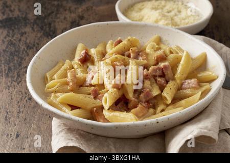 Pasta alla Carbonara. Penne con pancetta, uova, parmigiano e salsa alla panna. Cucina tradizionale italiana. Vista laterale, primo piano Foto Stock