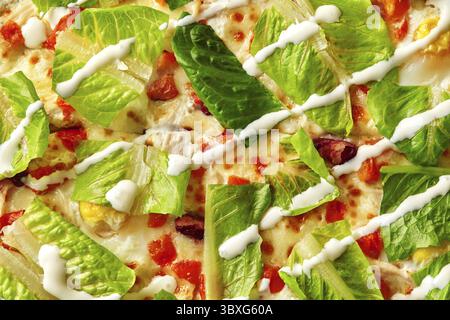 Primo piano di un'appetitosa pizza con insalata caesar con lattuga fresca alla romaina, condimento cremoso, pollo e parmigiano, per un sapore unico Foto Stock