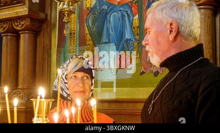 Felice anziani bella coppia sposata con i capelli grigi con candele in chiesa ortodossa Foto Stock