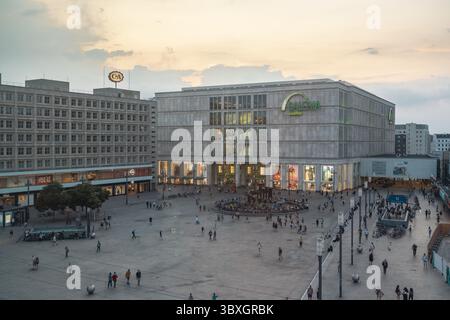Berlino, Germania - 27 agosto 2019: Veduta della Galeria Kaufhof, un faro di luce contro il cielo oscuro, pieno di vita ad Alexanderplatz, una sinfonia di movimento ed energia urbana. Foto Stock