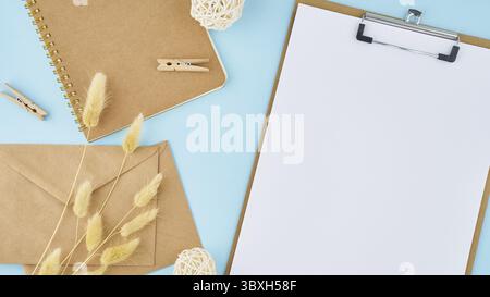 Concetto di zero rifiuti. Foglio bianco sulla clipboard, creare buste su un desktop moderno blu brillante per ufficio. Ecologico e naturale, larghezza lunga Foto Stock