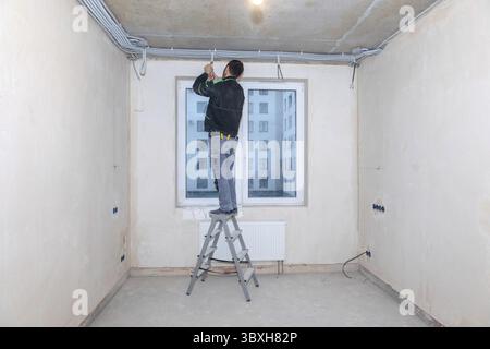 L'operatore elettrico controlla la tensione nei fili. Riparazione in nuovo appartamento, cablaggio elettrico. Foto Stock