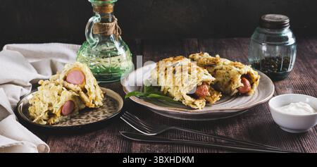 Cibo, salsicce avvolte in frittelle di cavolo tritate su un piatto su un banner a rete da tavolo Foto Stock