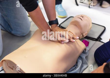 Primo piano delle mani che eseguono la RCP su un manichino di addestramento durante una classe di pronto soccorso Foto Stock