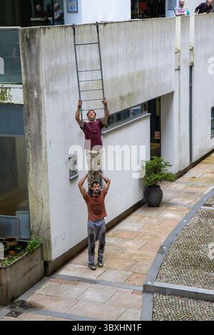 18 luglio 2025. Merchant City, Glasgow, Regno Unito. I due artisti di strada "Be Flat" eseguono il loro spettacolo "Follow me". Questo ha portato i partecipanti attraverso il festival, con la coppia che si arrampicava sugli edifici circostanti e si esibiva in acrobazie pericolose. Faceva tutto parte del Merchant City Festival di Glasgow. Crediti: Jacob Hughes/Alamy Live News Foto Stock