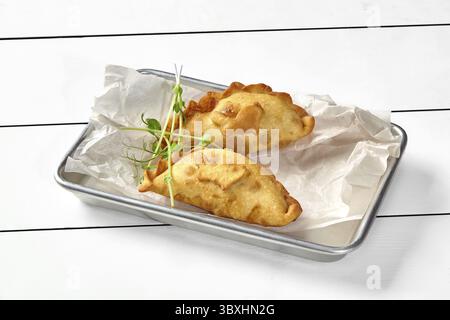 Salviette di pasta sfoglia cotte fino a quando non diventano dorate con delizioso ripieno salato di salmone, spinaci, formaggio spalmabile ed erbe aromatiche servite in vassoio metallico o. Foto Stock