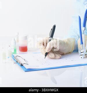 Pandemia di COVID-19, Coronavirus. Medico irriconoscibile nominare farmaci di prescrizione per i pazienti in ospedale in servizio, avvalersi per lavoro, compilare i moduli, c Foto Stock