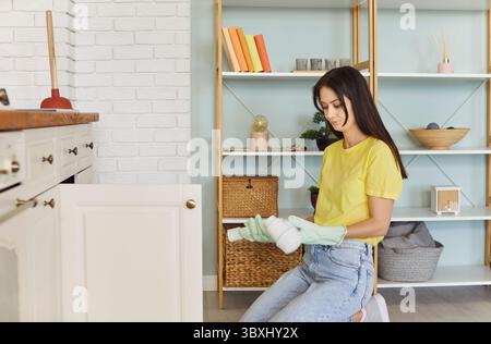 Giovane donna che soffre di problemi idraulici in cucina Foto Stock