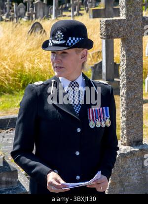 Eastbourne, East Sussex. 18 luglio 2025. I rappresentanti della polizia del Sussex, della Federazione di polizia e degli amici del cimitero di Ocklynge assistono all'inaugurazione della lapide restaurata all'ispettore della polizia del Sussex Arthur Walls, ucciso in servizio nel 1912. L'ispettore Walls ha assistito ai rapporti di un uomo nascosto sul tetto di un indirizzo a South Cliff Avenue Eastbourne, sfidando il sospetto, sono stati sparati due colpi, uno che colpisce l'agente nel petto uccidendolo all'istante. Il suo assassino di 29 anni, John Williams, vero nome, George Mackay, un piccolo criminale, fu arrestato a Londra. E' stato condannato per il mu Foto Stock