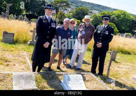 Eastbourne, East Sussex. 18 luglio 2025. I rappresentanti della polizia del Sussex, della Federazione di polizia e degli amici del cimitero di Ocklynge assistono all'inaugurazione della lapide restaurata all'ispettore della polizia del Sussex Arthur Walls, ucciso in servizio nel 1912. L'ispettore Walls ha assistito ai rapporti di un uomo nascosto sul tetto di un indirizzo a South Cliff Avenue Eastbourne, sfidando il sospetto, sono stati sparati due colpi, uno che colpisce l'agente nel petto uccidendolo all'istante. Il suo assassino di 29 anni, John Williams, vero nome, George Mackay, un piccolo criminale, fu arrestato a Londra. E' stato condannato per il mu Foto Stock