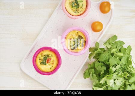 Muffin, paleo, keto dieta. Frittata con spinaci, verdure, pomodori cotti in piccoli stampi Foto Stock