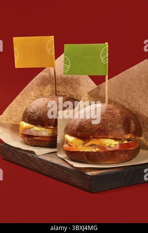 Due hamburger freschi con bandiere piccole su un asse di legno, ideali per rappresentare una catena di ristoranti fast food Foto Stock