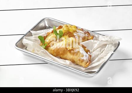 Croccanti e friabili boccali di pasta sfoglia con delicato ripieno di mele al gusto di cannella ricoperto di fette di frutta, rametto di miglio fresco Foto Stock