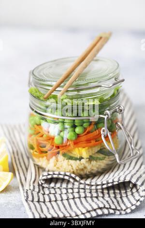 Vaso in vetro con verdure fresche crude e couscous groats. Prep pasto sano - foto di preparazione ricetta. Piatti vegani sani in contenitori di vetro. Weig Foto Stock