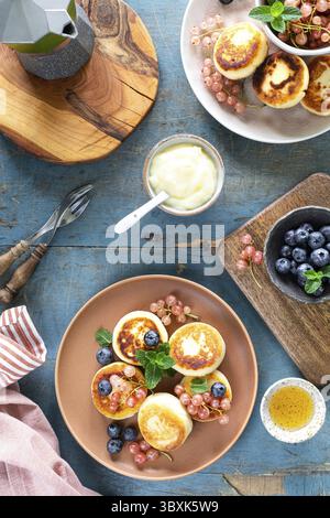 Cibo, deliziosi pancake al formaggio sono serviti con miele e frutti di bosco. Piatti della cucina russa e Ucraina Foto Stock