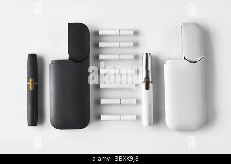 Nuova generazione, nero e bianco, due sigarette elettroniche e due batterie aperte, sette bastoni termici isolati su bianco. Riscaldamento del tabacco. Templat Foto Stock